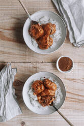 From above top view of bowls of rice and delicious lentil meatballs with curry sauce placed near spice and napkin on wooden table at home - ADSF13043