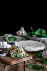 From above of tasty tortilla stuffed with puree of spinach on wooden table with ingredients - ADSF13048