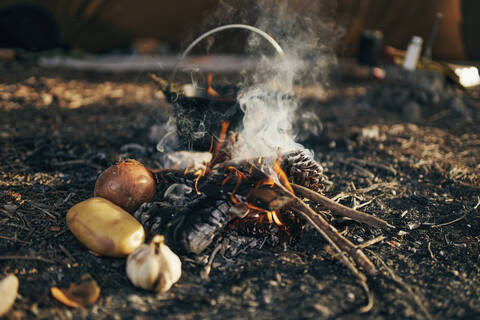 Surface level of cooking food over flames from campfire stock photo