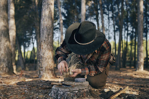 Bushcrafter preparing fire to cook food in forest stock photo