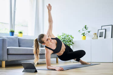 Woman learning side plank exercise on internet through digital tablet - BSZF01657