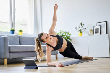 Woman doing side plank exercise in living room at home - BSZF01658