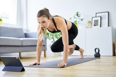 Determined woman learning mountain climber exercise through internet on digital tablet - BSZF01664