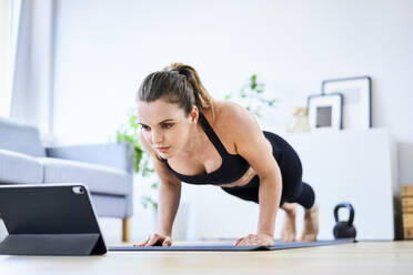 Woman learning exercise on internet through tablet PC at home - BSZF01666