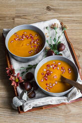 From above arrangement with creamy pumpkin soup with chestnut and pomegranate seeds in bowl with spoon - ADSF13117