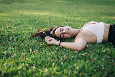 Woman napping while lying on grass at park - DCRF00763