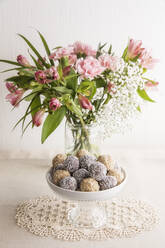 Jar of pink blooming flowers and bowl of protein balls - EVGF03709