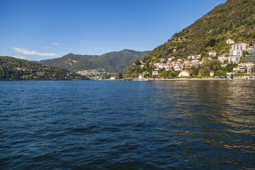 Town at lakeshore of Lake Como against sky on sunny day - FLMF00281