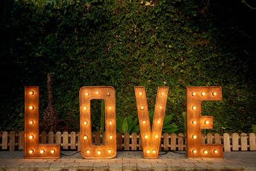 Installation von Holzbuchstaben mit Glühbirnen, die am Abend während der Hochzeitsfeier im Innenhof aufgestellt werden - ADSF13249