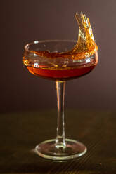Glänzendes Glas Alkohol-Cocktail garniert mit karamellisiertem Zucker gesponnen auf Holztisch in Bar platziert - ADSF13299
