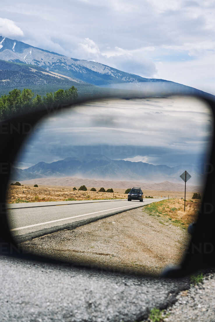 Ein Auto fährt auf einer asphaltierten Straße vor dem Hintergrund von  Bergen und spiegelt sich im