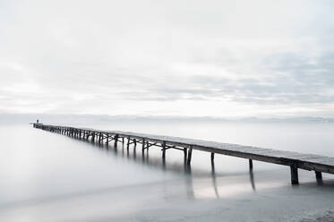 Peaceful scenery of sea with long wooden quay during foggy morning in Playa de Alcudia in long exposure - ADSF13389
