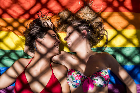 Lesbisches Paar auf Regenbogenflagge liegend - ADSF13444