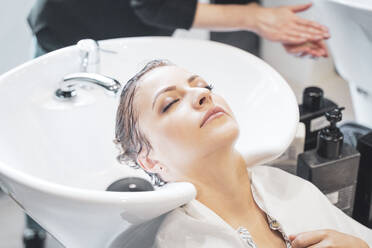 Friseurin wäscht Haare einer jungen Frau - ADSF13472