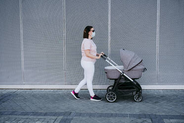 Mutter mit Schutzmaske und Spaziergang mit Kinderwagen - EBBF00647