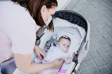 Mutter mit Schutzmaske, schlafendes kleines Mädchen im Kinderwagen - EBBF00649