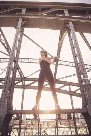 Woman stretching out arms on metal bridge at sunset stock photo