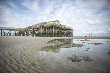 Deutschland, Schleswig-Holstein, Sankt Peter-Ording, Sandiger Küstenstrand mit Seebrücke im Hintergrund - ASCF01415