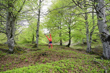 Active woman doing handstand in beech forest - ECPF01009