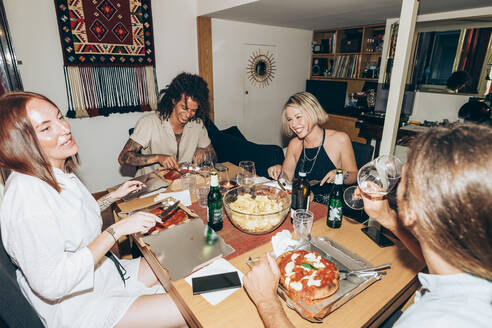 Fröhliche Freunde essen Pizza während einer Party zu Hause - MEUF01981