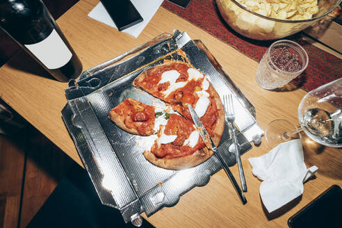 Pizza slices on table during party at home - MEUF01982