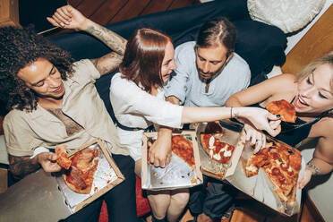 Freunde genießen Pizza beim geselligen Beisammensein zu Hause - MEUF01991