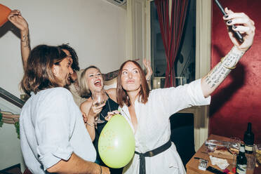 Fröhliche Freunde machen ein Selfie beim Tanzen auf einer Party zu Hause - MEUF01997