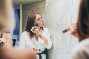 Reflection of young woman applying make-up in bathroom - MEUF02005