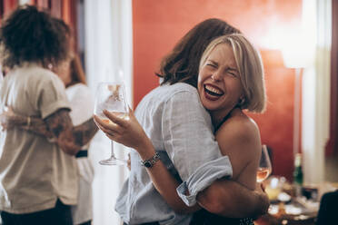 Glückliche junge Frau umarmt männlichen Freund während einer Party zu Hause - MEUF02018