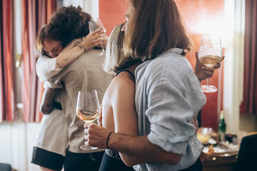 Männliche und weibliche Freunde umarmen sich während einer Party zu Hause - MEUF02019