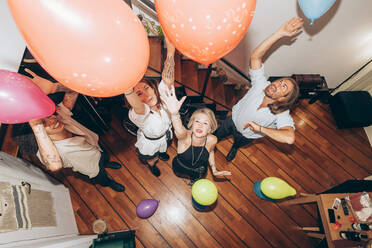 Fröhliche Freunde tanzen mit bunten Luftballons während einer Party zu Hause - MEUF02021