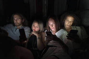 Male and female friends using smart phones at night - MEUF02022