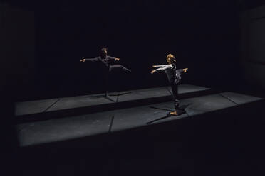 Male and female dancer performing comtemporary ballet on black stage - NGF00606