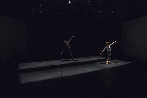 Male and female dancer performing comtemporary ballet on black stage - NGF00607