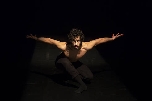 Male ballet dancer performing on black stage - NGF00614