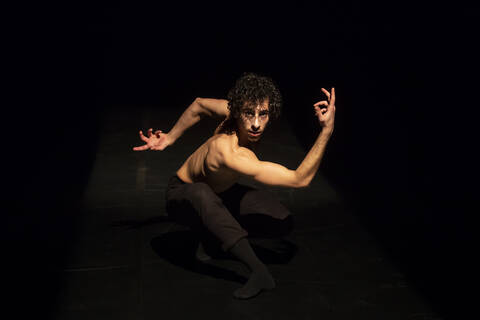 Male ballet dancer performing on black stage stock photo