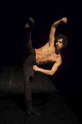 Male ballet dancer performing on black stage - NGF00616