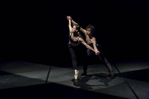 Male and femal dancer performing contemporary ballet on black stage stock photo