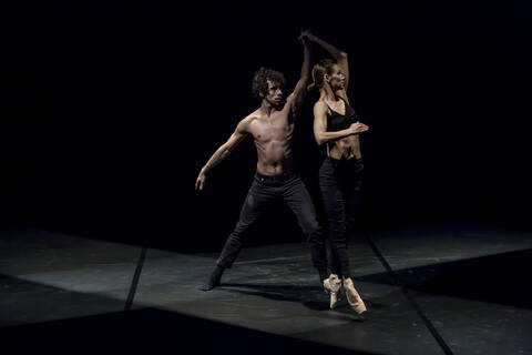 Male and femal dancer performing contemporary ballet on black stage stock photo