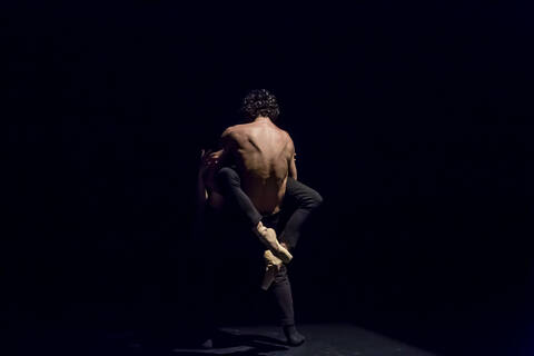 Tänzer und Tänzerin beim zeitgenössischen Ballett auf schwarzer Bühne, lizenzfreies Stockfoto