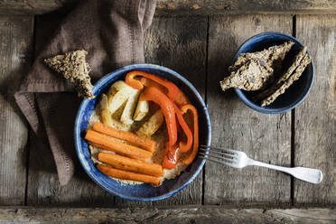 Hausgemachte Cracker und eine Schüssel veganer Hummus mit gebratenen Karotten und Paprika - EVGF03725