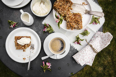 Tasse Kaffee und hausgemachter Rhabarberkuchen auf dem Kaffeetisch im Garten - EVGF03736