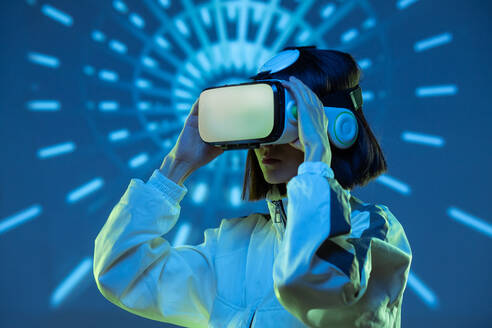 Aufgeregte junge Frau mit Virtual-Reality-Erfahrung im Neonlicht - ADSF13645