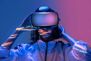 Aufgeregte junge Frau mit Virtual-Reality-Erfahrung im Neonlicht - ADSF13654