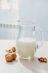 Glas mit Milch und Nüssen auf dem Tisch - ADSF13725