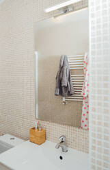 Weiche Bademäntel spiegeln sich im Spiegel eines modernen Badezimmers mit Keramikwaschbecken und -fliesen - ADSF13757