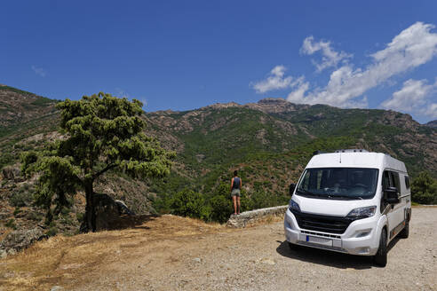 Frankreich, Corse-du-Sud, Piana, Van geparkt in Calanques de Piana mit Frau, die die umliegende Landschaft im Hintergrund bewundert - UMF00991