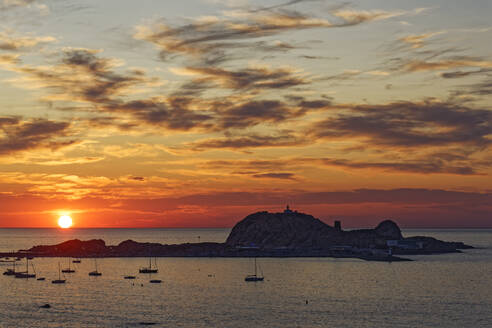 Frankreich, Haute-Corse, LIle-Rousse, Silhouetten von Segelbooten vor einer kleinen Mittelmeerinsel bei stimmungsvollem Sonnenuntergang - UMF01002