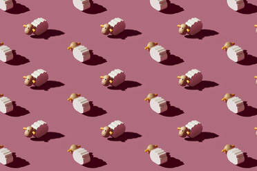 Pattern of small white sheep figurines against red background - ERRF04316