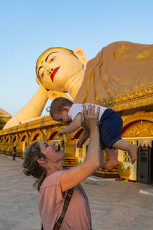 Myanmar, Mon-Staat, Mutter hält kleines Mädchen vor der riesigen Statue eines liegenden Buddhas im Pupawadoy-Kloster - RUNF04105